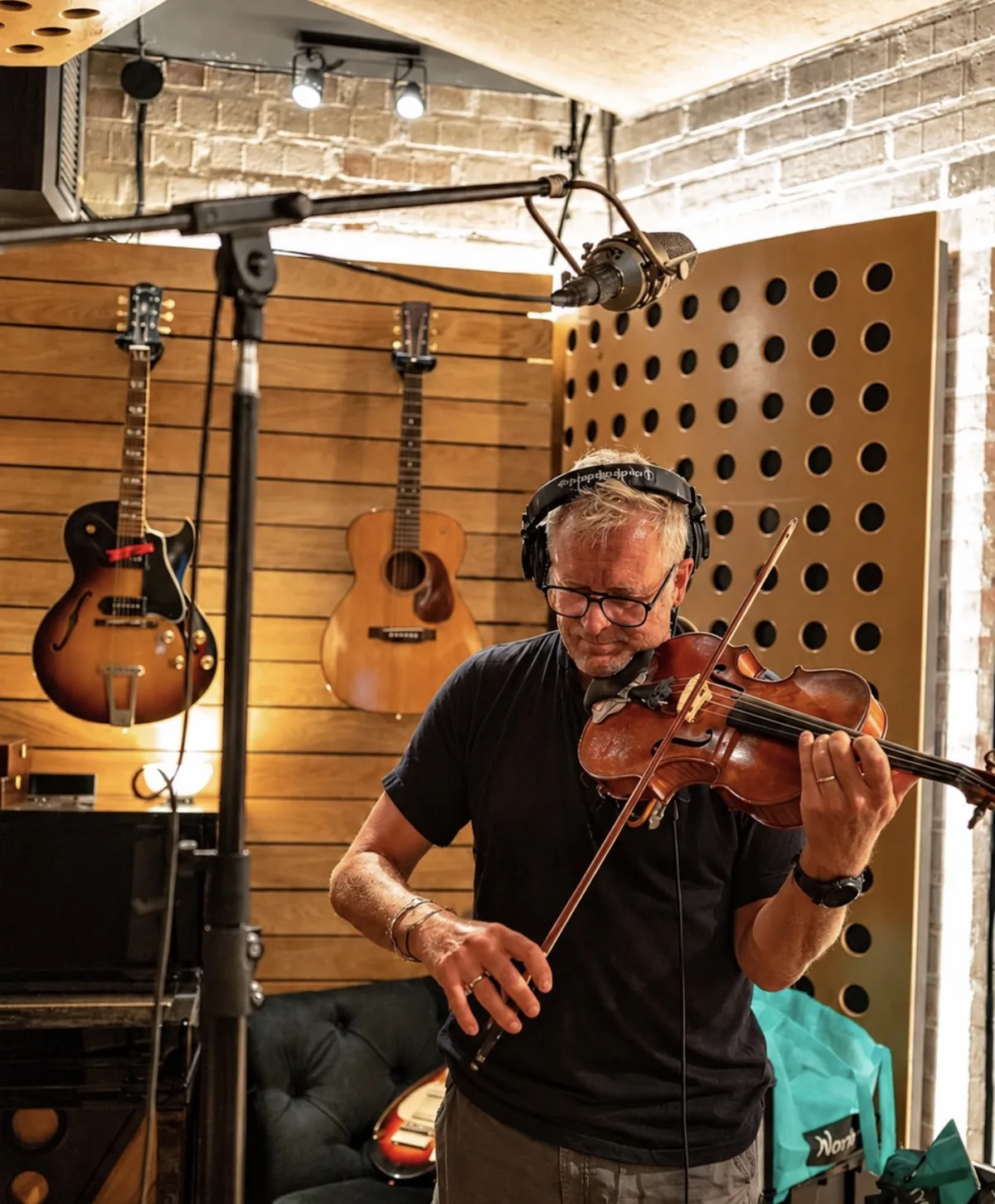 Bruce White playing viola in the BXA studio, wearing headphones